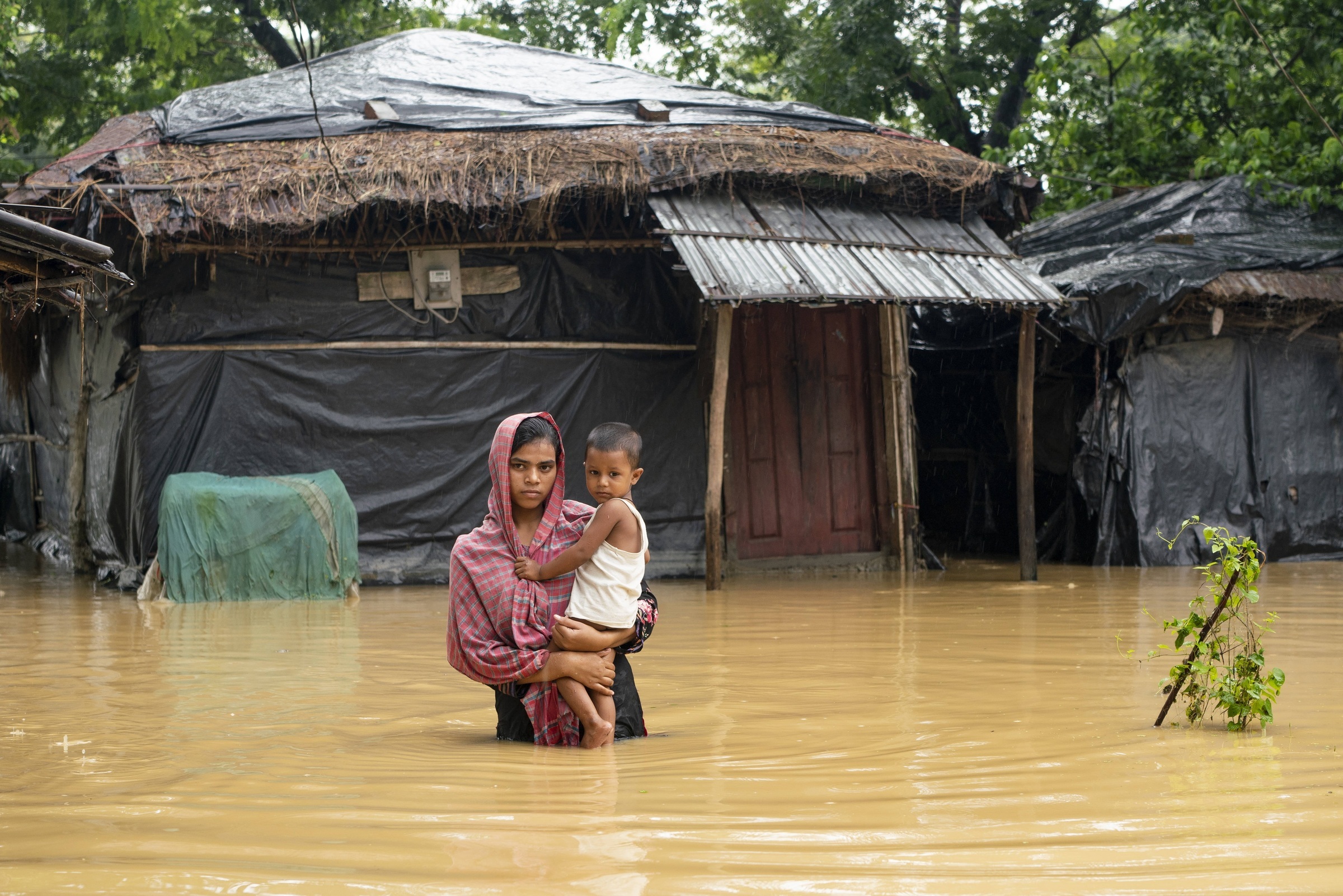 Eine Mutter trägt ihr Kind auf dem Arm bei einer Überschwemmung in Bangladesch (Foto: Zakir Hossain) Eine Mutter trägt ihr Kind auf dem Arm bei einer Überschwemmung in Bangladesch (Foto: Zakir Hossain)
