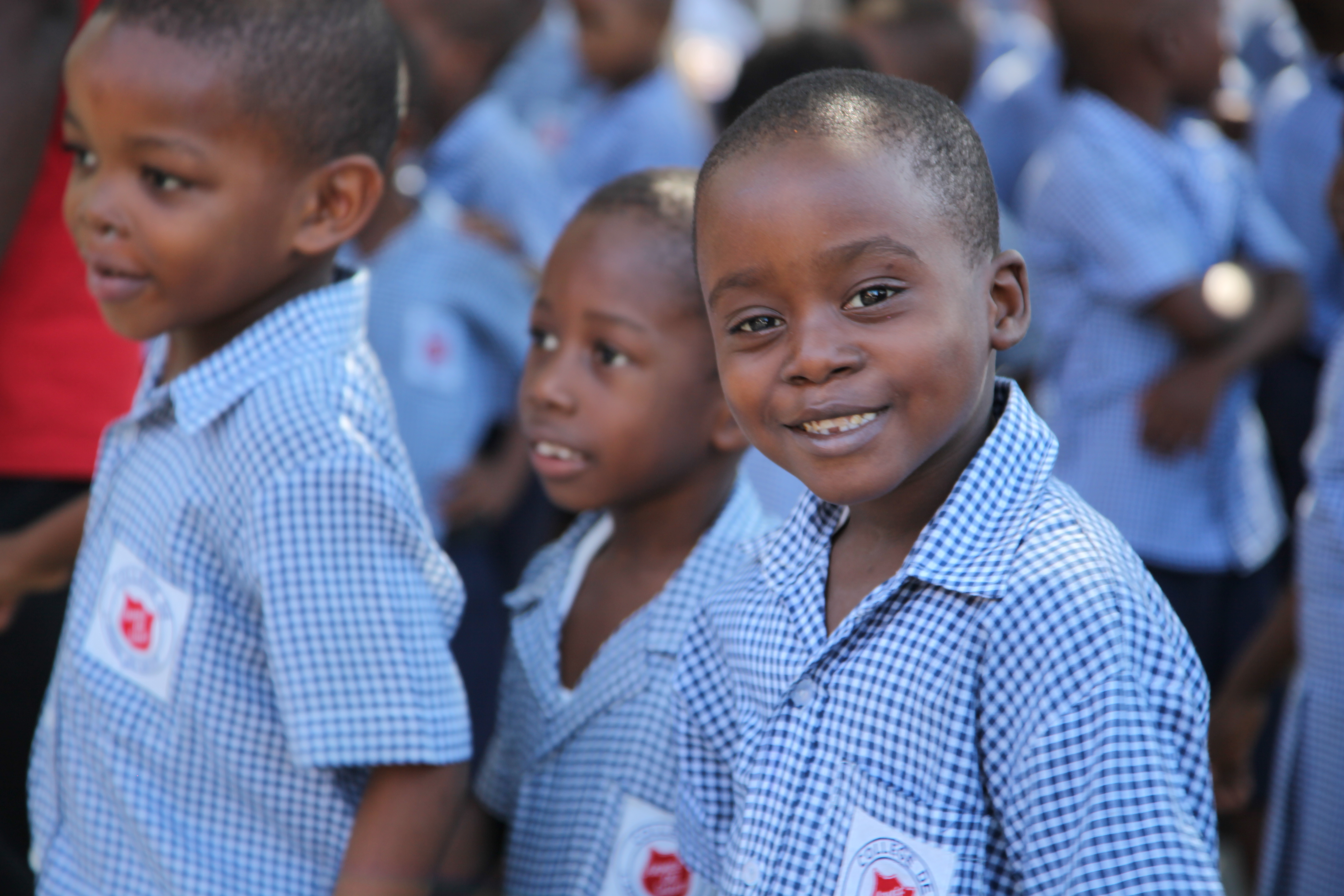 Schuljungen aus Haiti lächeln schüchtern und tragen weiß-blau karierte Schuluniformen. (Quelle: Katja Anger)