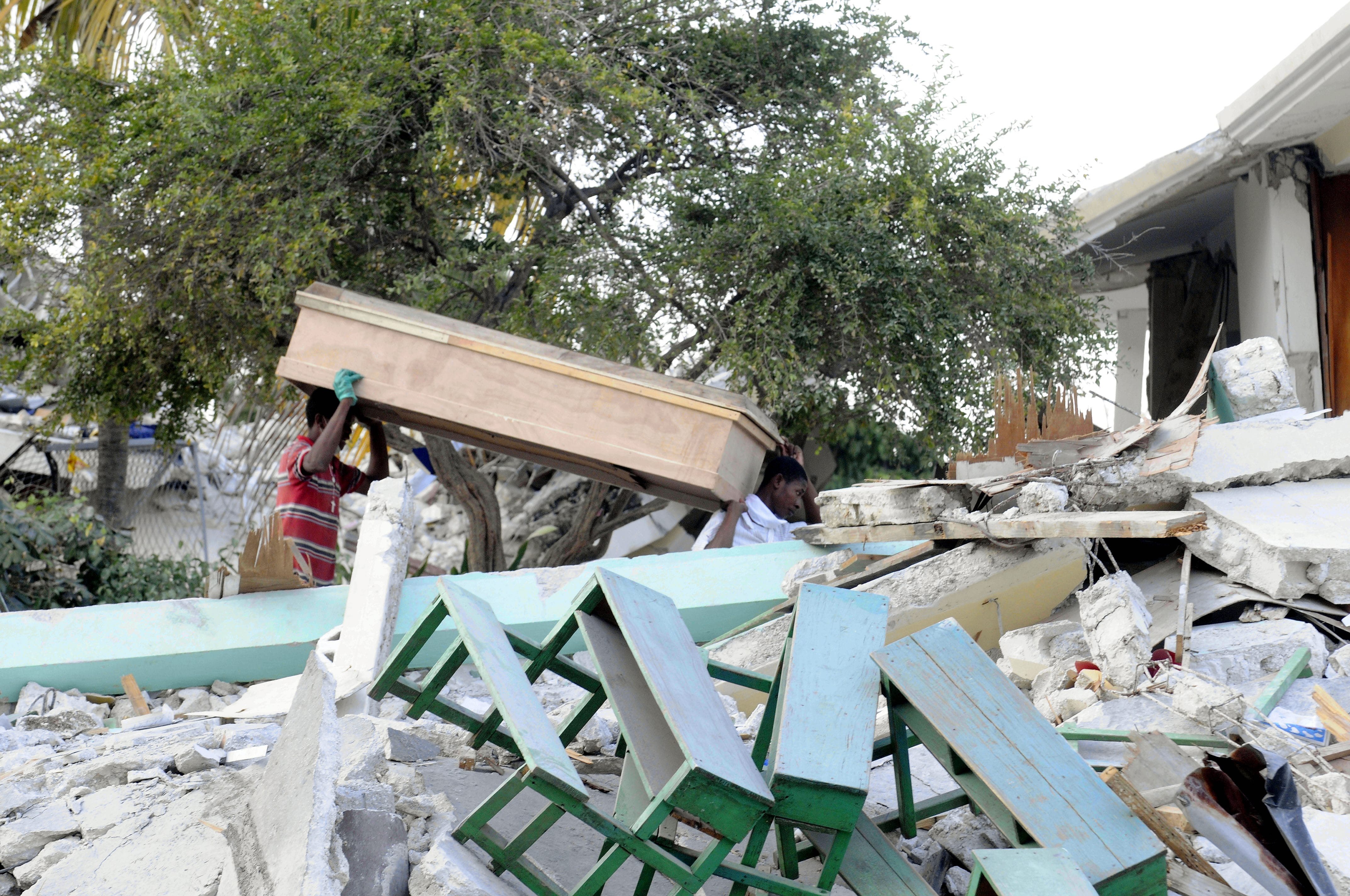 Ein Freiwilliger sucht in Trümmern nach Überlebenden und trägt dabei einen Sarg auf den Schultern. (Quelle: Benjamin Weinkauf/BILD)