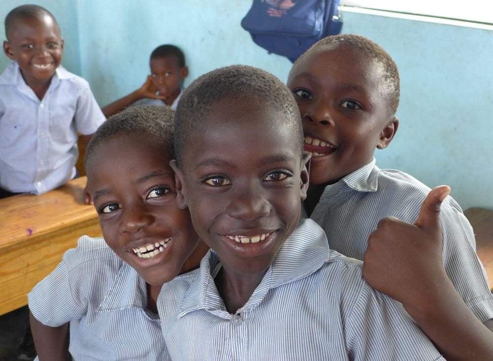 Drei Jungen in einem Klassenzimmer lachen freudestrahlend. (Quelle: Kathrin Meindl)
