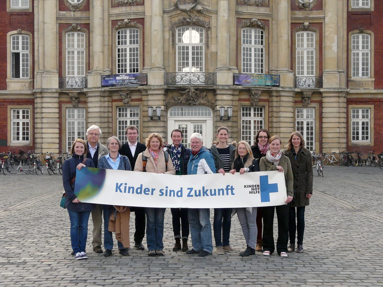 Gruppenfoto des Arbeitskreises Münster mit einem Kinder sind Zukunft Banner. 