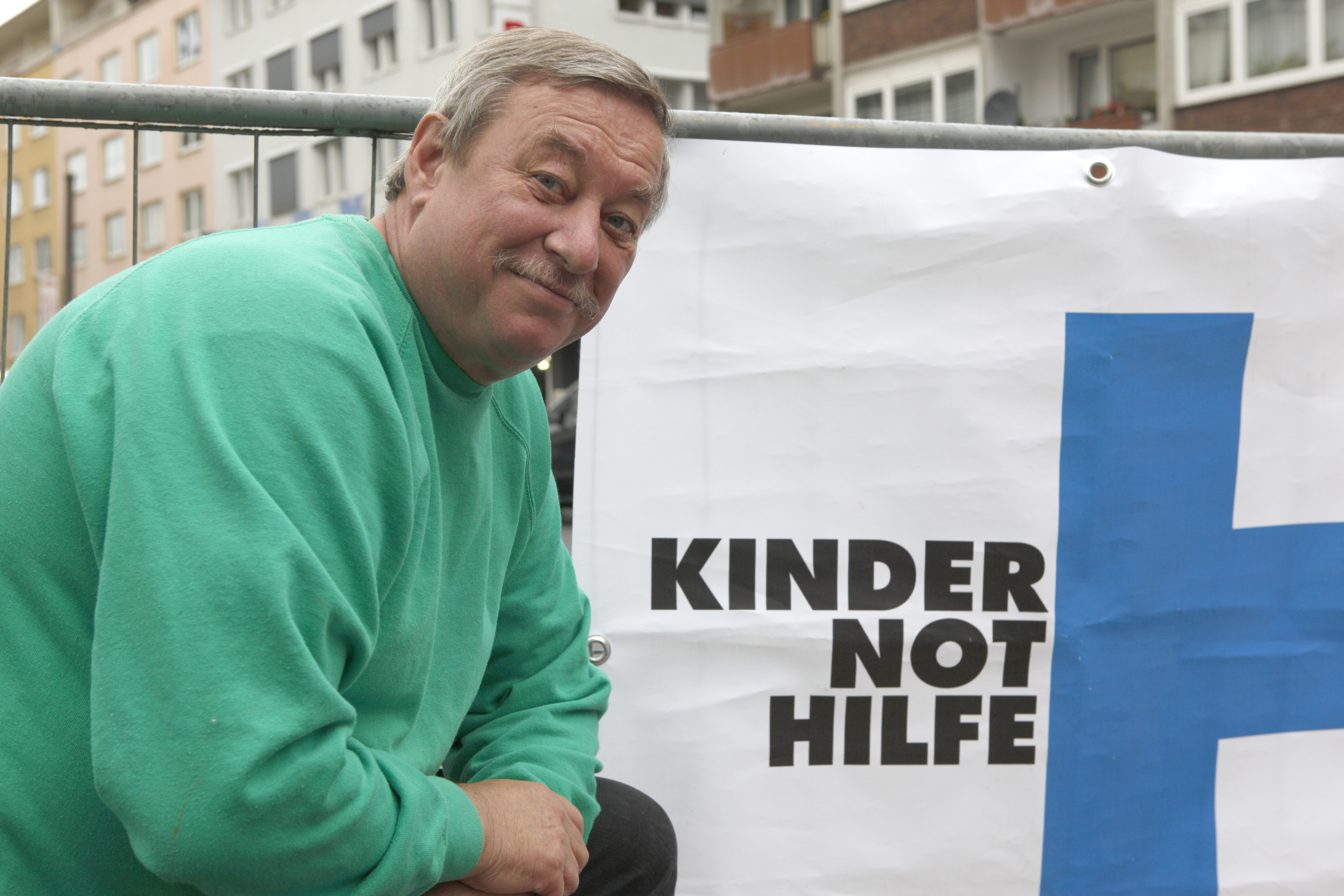 Christian Biemann hockt vor einem Kindernothilfebanner