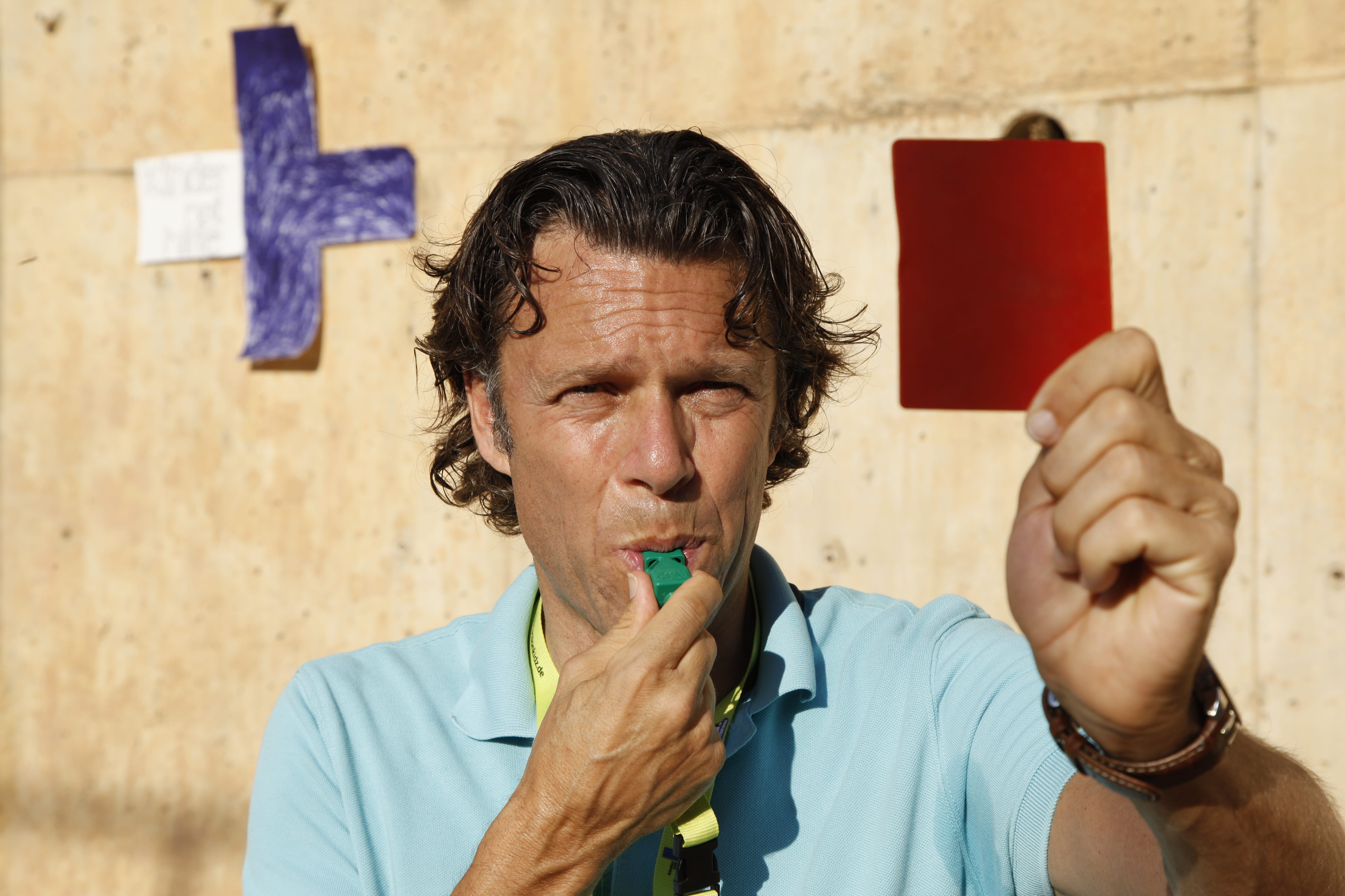 Urs Meier zeigt hat eine Pfeife im Mund und zeigt eine rote Karte