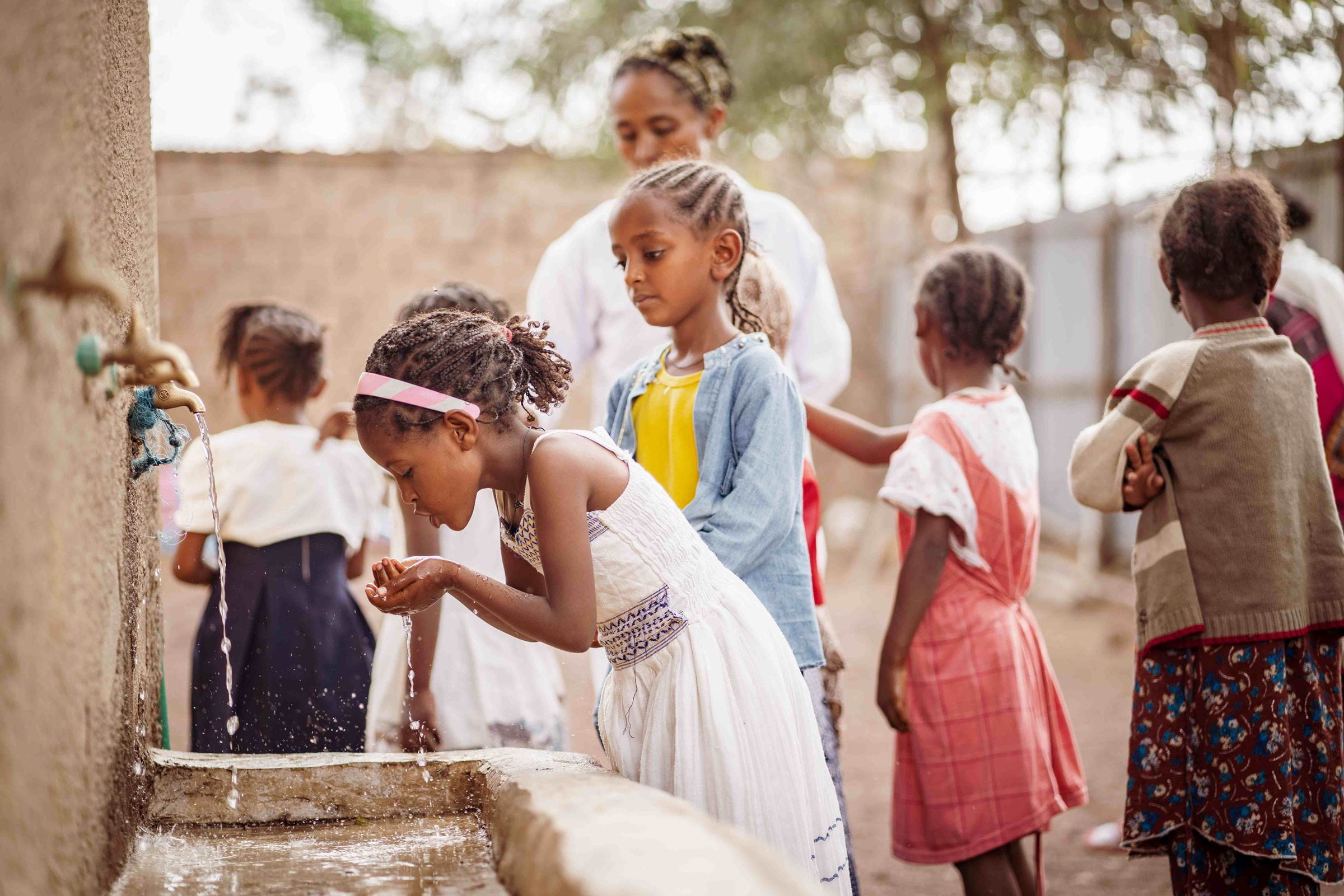 Ein Mädchen aus Äthiopien trinkt sauberes Wasser aus einem Wasserhahn. (Quelle: Jakob Studnar)