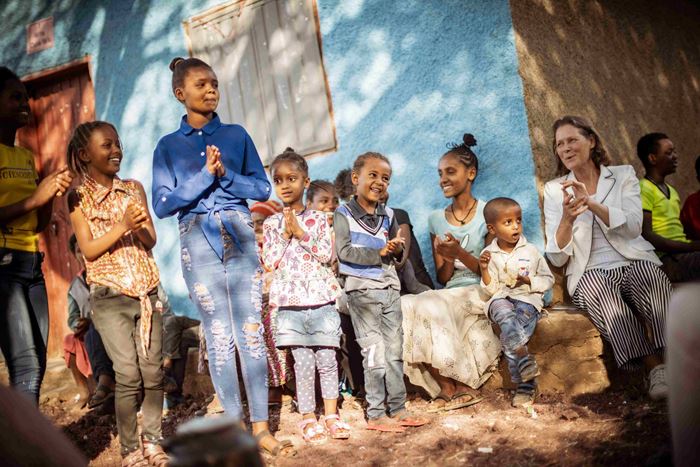 Mädchen in Äthiopien sitzen und stehen im Halbschatten mit Christina Rau, alle haben Spaß und klatschen.  (Quelle: Jakob Studnar)