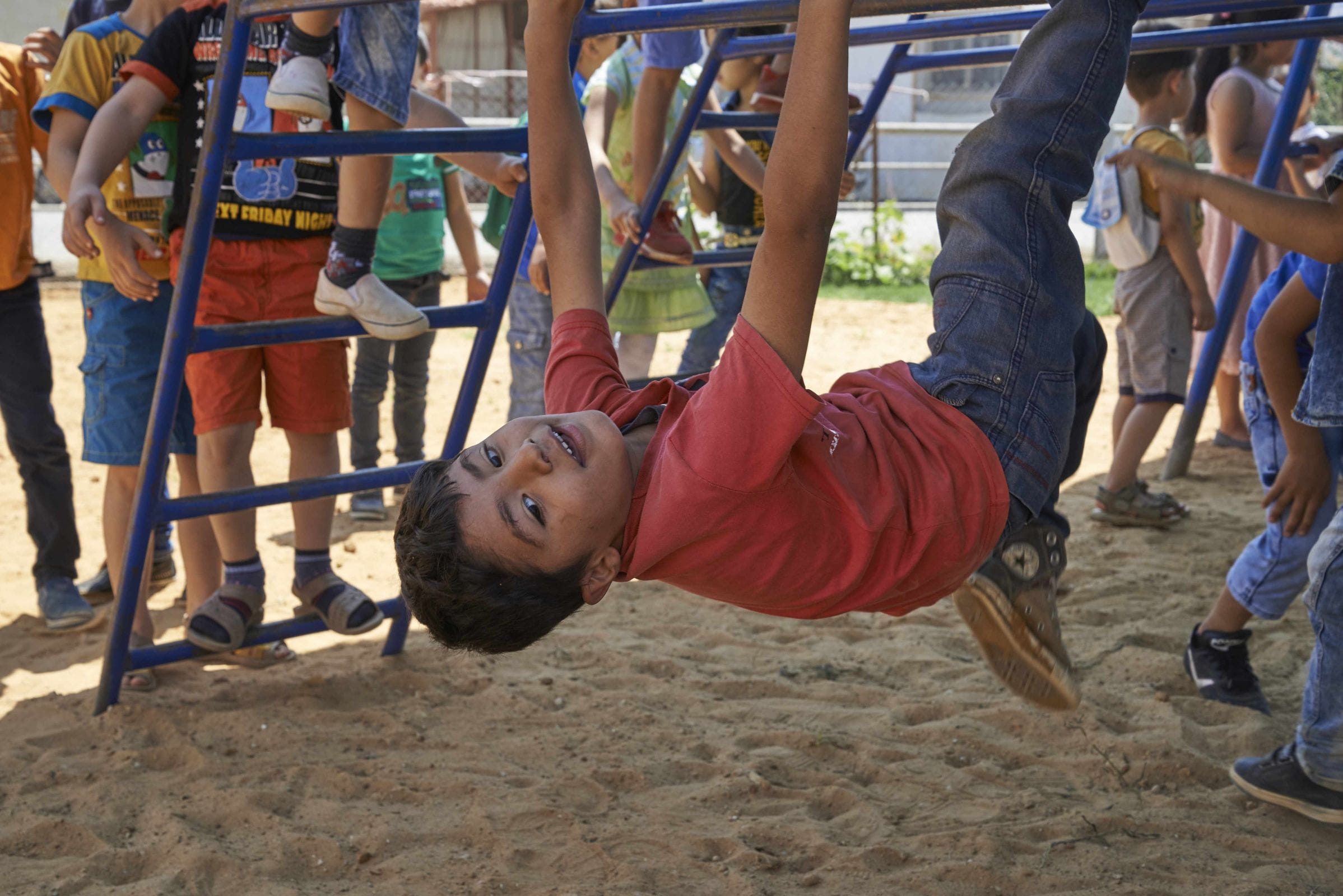 Ein syrischer Junge im Libanon hängt kopfüber an einem Klettergerüst. (Quelle: Ulrich Gernhardt) Ein syrischer Junge im Libanon hängt kopfüber an einem Klettergerüst. (Quelle: Ulrich Gernhardt)