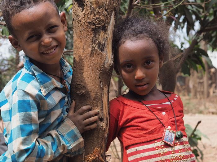 Ein Junge und ein Mädchen aus Äthiopien stehen Arm in Arm und lächeln. (Quelle: Malte Pfau)