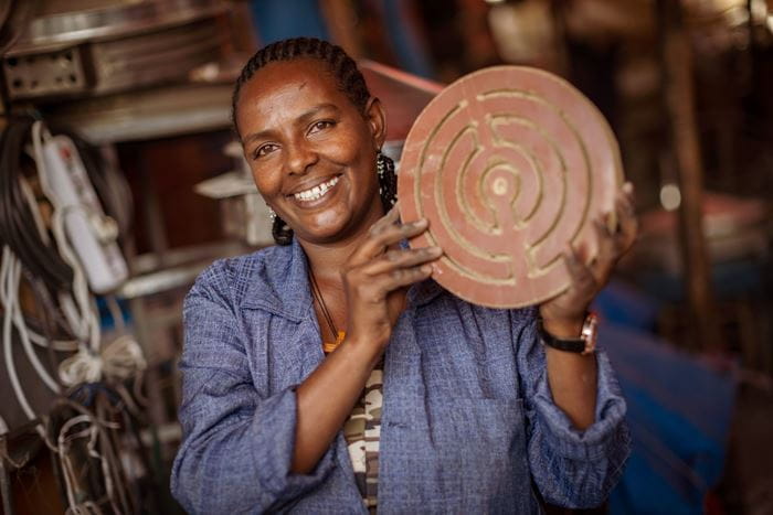 Eine Frau hält eine kleinen Ofen zum Injerabacken hoch, den sie selbst repariert hat. (Quelle: Jakob Studnar)