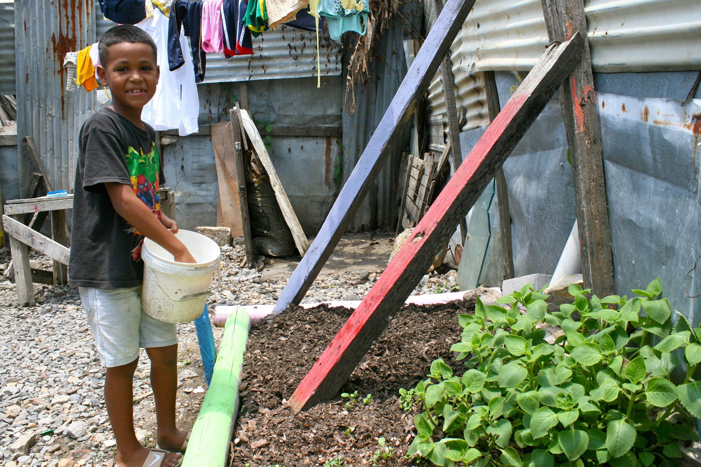 Ein Junge gießt Pflanzen in einem Küchengarten. (Quelle: Jürgen Schübelin)