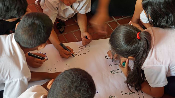 Kinder in Honduras hocken über einem Blatt Papier und malen. (Quelle: Lorenz Töpperwien)