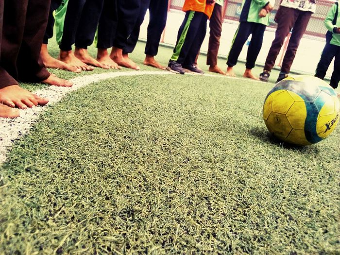 Ein Fußball liegt auf dem Boden. Darum herum stehen Kinder barfuß. (Quelle: Jenifer Girke)