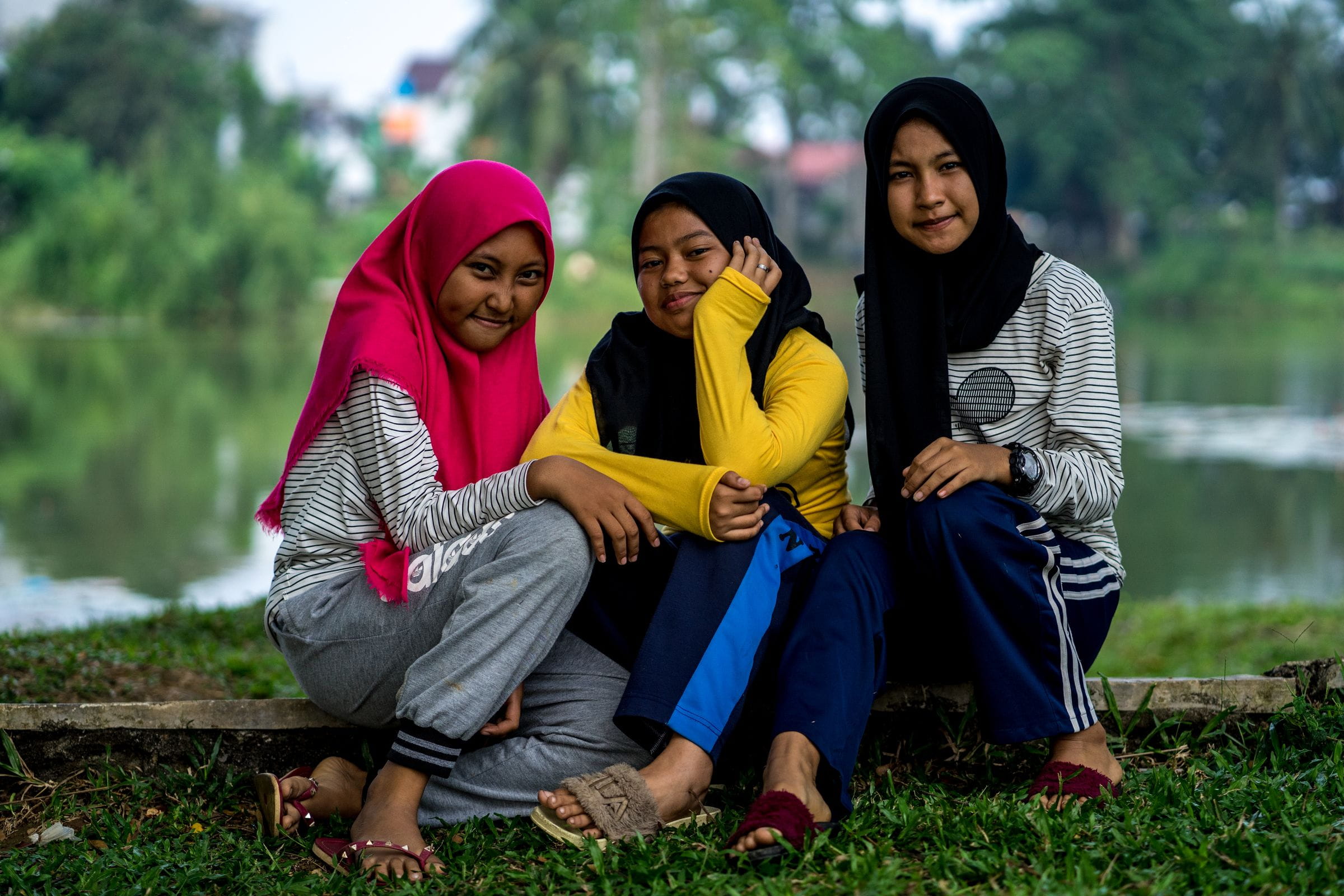 Drei Mädchen aus Indonesien sitzen an einem Seeufer und lächeln schüchtern. (Quelle: Lennart Zech)