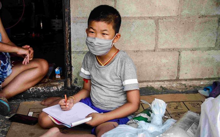 Ein Junge aus Thailand sitzt mit Maske auf dem Boden. (Quelle: Kindernothilfe-Partner)