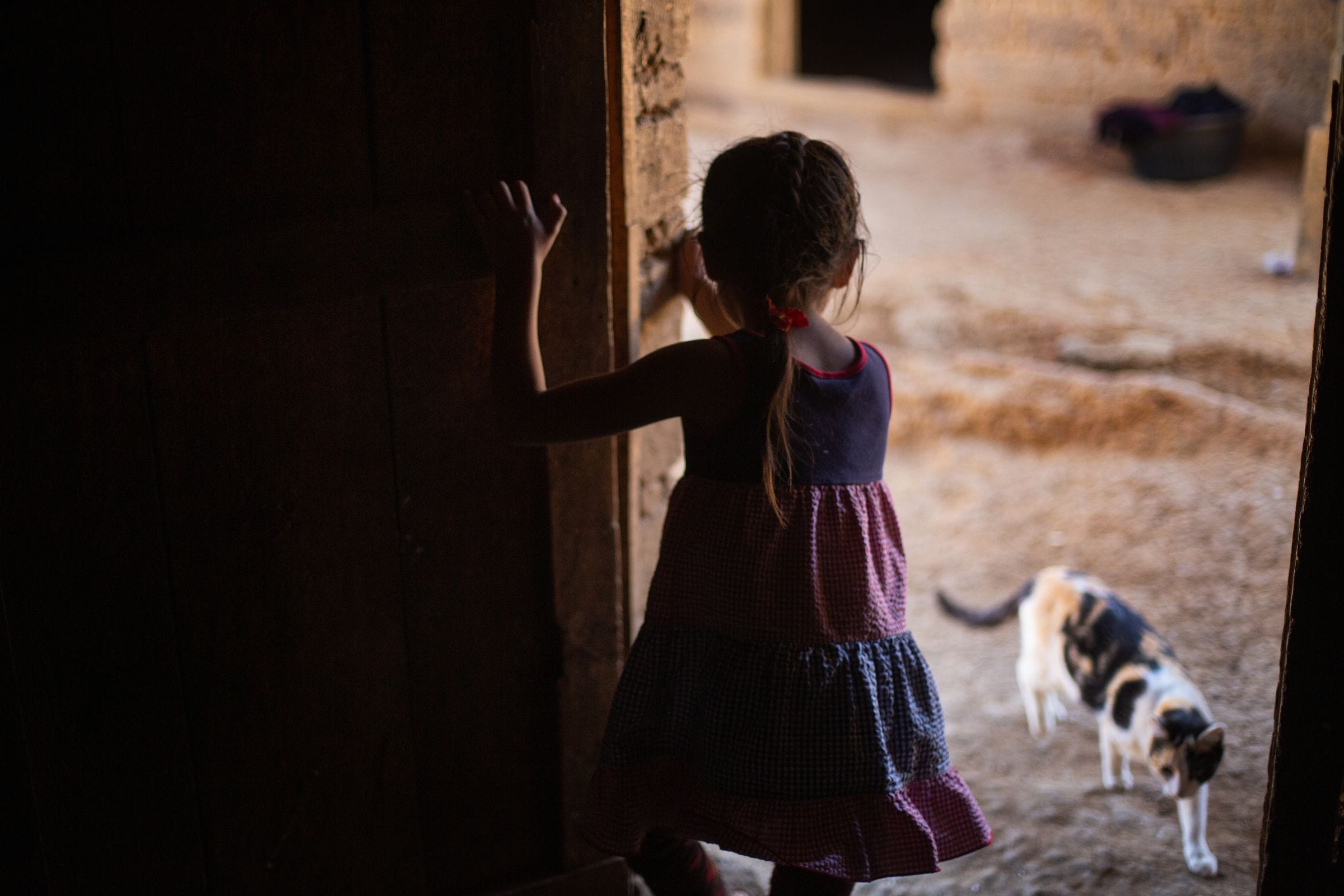 Ein kleines Mädchen steht in einem Hauseingang im Schatten, sie ist nur von hinten zu sehen. (Quelle: James Rodriguez)