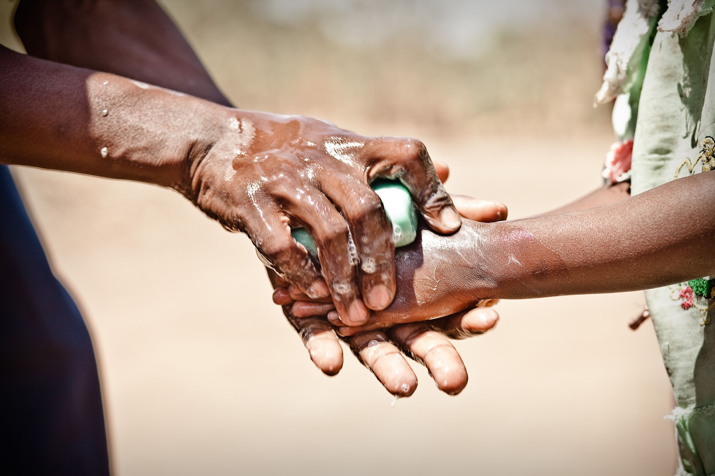 Ein Erwachsener wäscht einem kleinen Kind die Hände mit Seife (Quelle: Jakob Studnar)