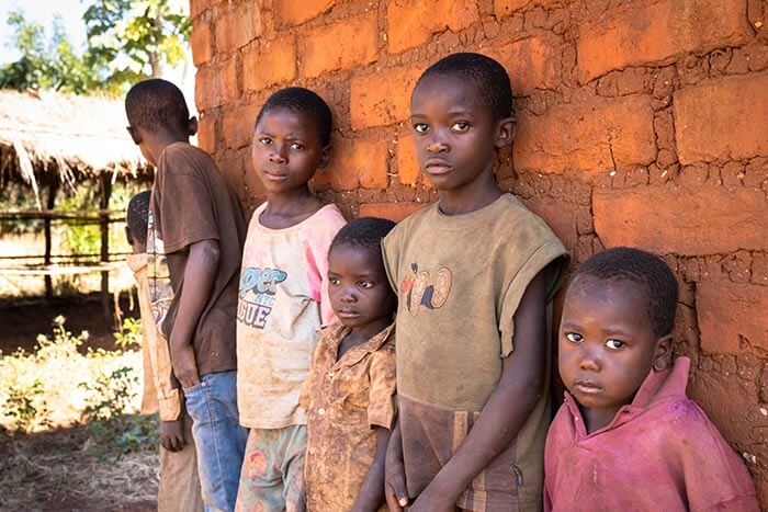 Vier Kinder aus Sambia stehen mit ernsten Gesichtern an einer Wand.  (Quelle: Kindernothilfe)