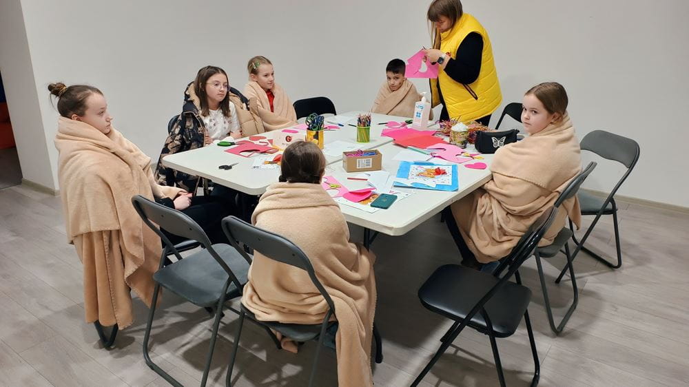 Kinder sitzen in Decken gehüllt am Tisch (Quelle: NGO Girls)