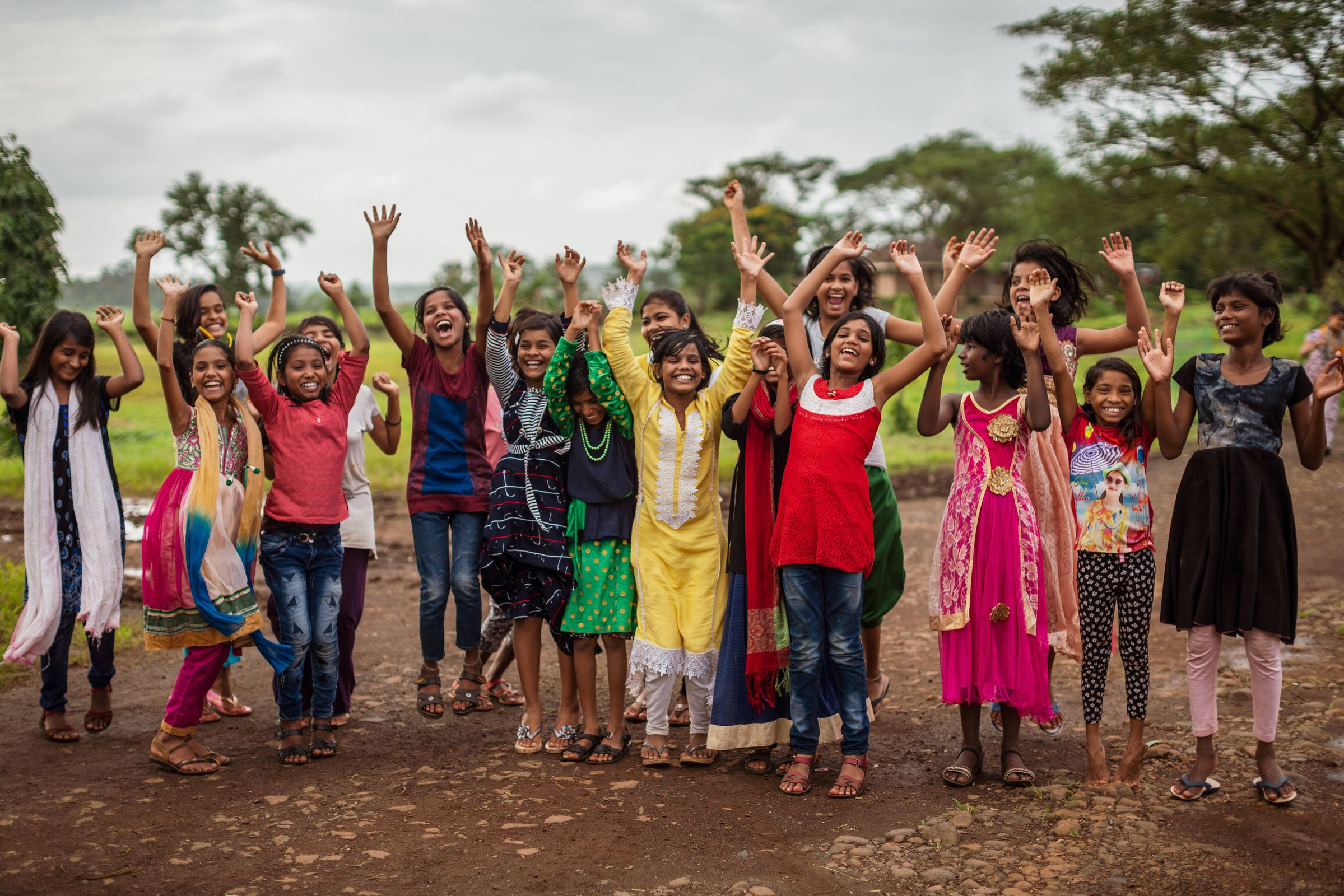 Eine Mädchengruppe aus Indien trägt bunte Kleider und lacht und winkt. (Quelle: Jakob Studnar)