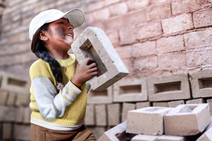 Ein Mädchen schleppt einen Ziegelstein (Quelle: Christian Herrmanny)
