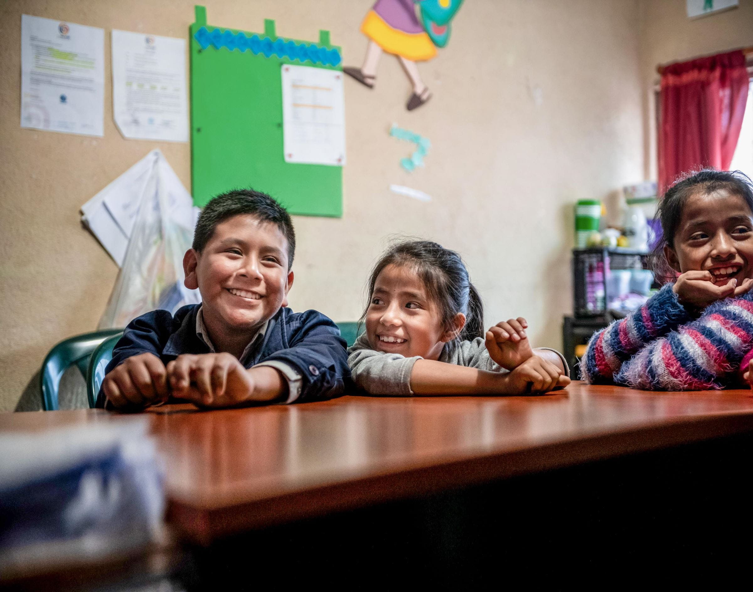 Drei Kinder aus Guatemala sitzen an einem Tisch und lachen. (Quelle: Fabian Strauch)