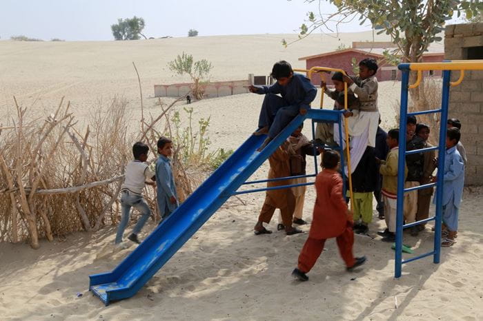 Mehrere Kinder spielen auf einem Spielplatz in einer wüstenähnlichen Gegend. (Quelle: Christine Idems)