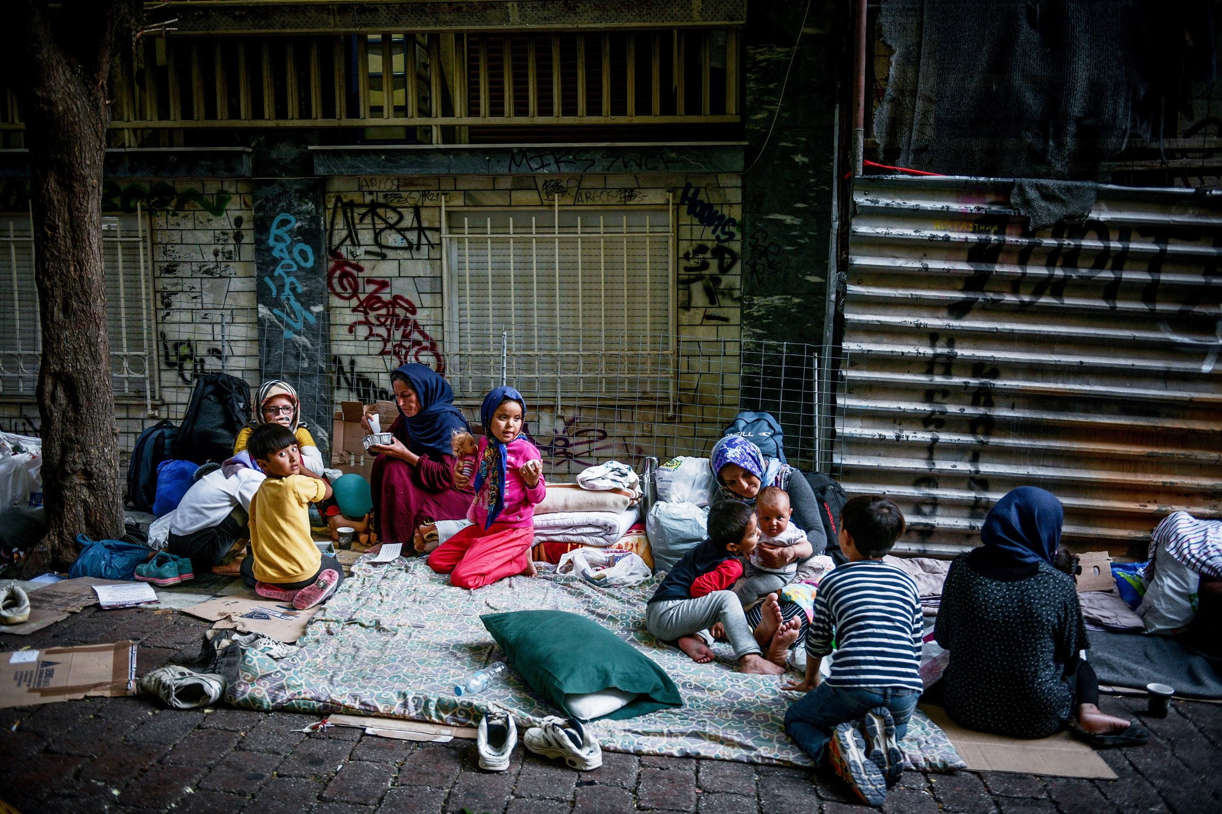 Frauen und Kinder, die geflüchtet sind, sitzen auf der Straße auf Decken und Kartons. (Quelle: picture alliance/Tatiana Bolari)
