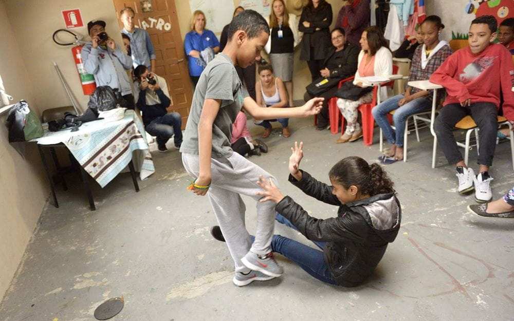Reportage Brasilien: Zwei Kinder stellen eine Gewaltszene nach, andere Kinder und Erwachsene schauen zu (Quelle: Florian Kopp / Kindernothilfe) Reportage Brasilien: Zwei Kinder stellen eine Gewaltszene nach, andere Kinder und Erwachsene schauen zu (Quelle: Florian Kopp / Kindernothilfe)