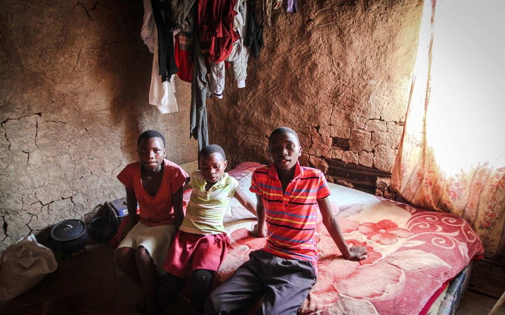 Foto: Drei Jugendliche sitzen auf einem Bett in einer ärmlichen Hütte (Quelle: Ralf Krämer, Kindernothilfe)