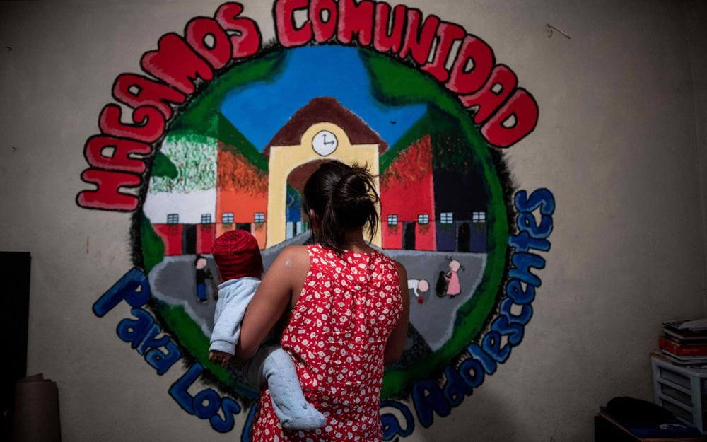 Reportage Guatemala; Foto: Junge Mutter und ihr Kind schauen auf Wand mit Bild (Quelle: Fabian Strauch / Kindernothilfe)
