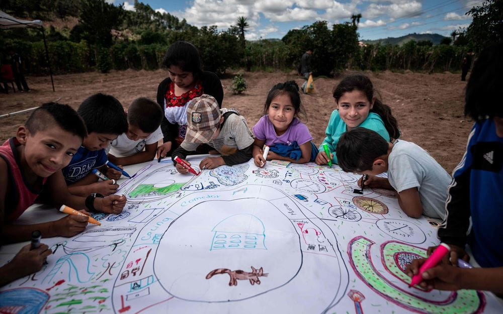 Reportage Guatemala; Foto: Kinder sitzen um ein großes Plakat herum und malen ihre Vorschläge (Quelle: Fabian Strauch / Kindernothilfe)