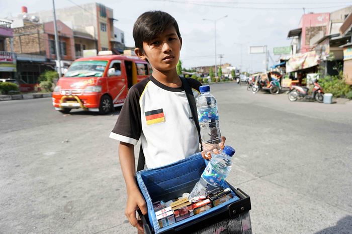 Ein Junge mit einem Bauchladen geht über eine Straße (Quelle: Christiane Dase)