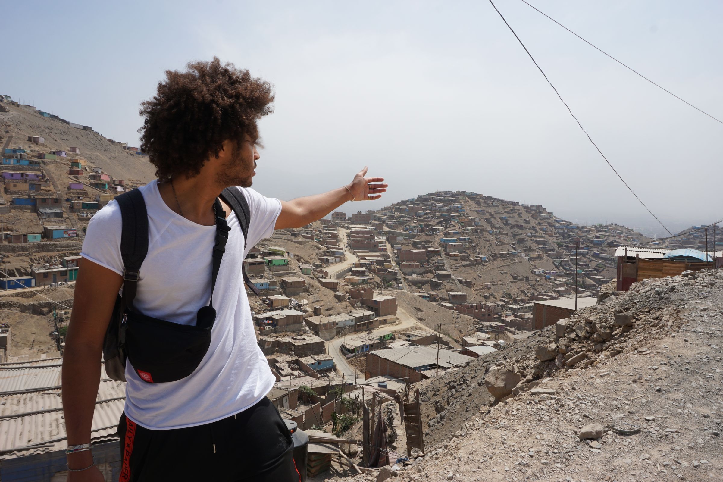 Dillan macht eine zeigende Geste in einer peruanischen Siedlung