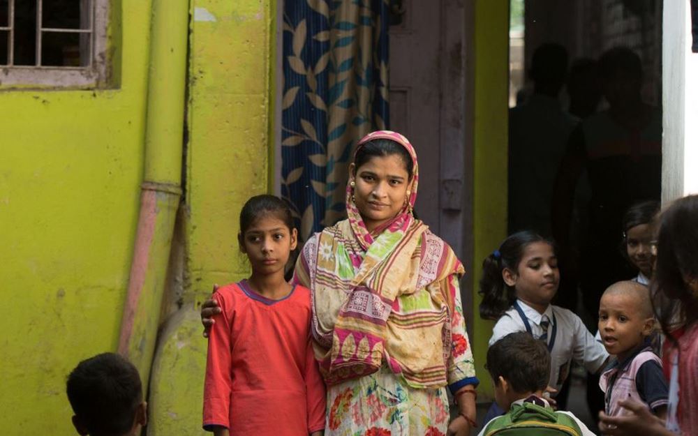 Reportage Indien: Sechs Monate, die den Unterschie machen; Foto: Mutter mit Kind lächeln in die Kamera (Quelle: Christian Nusch)