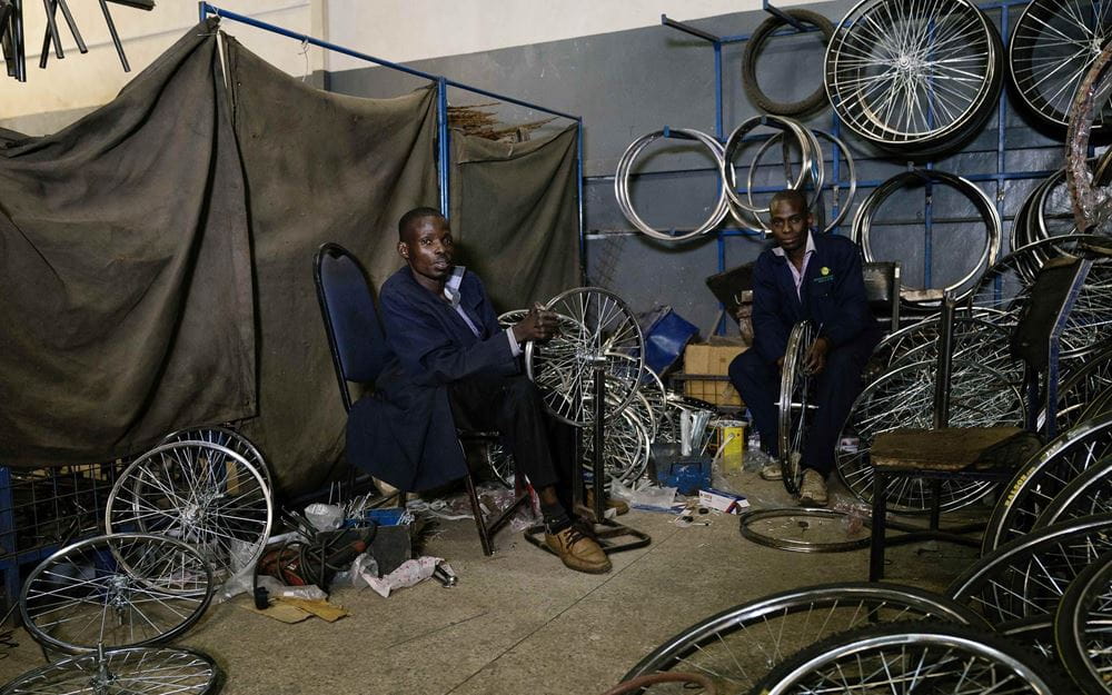 Reportage Kenia: Ein Alltag auf neun Quadratmetern; Foto: Zwei Männer bei der Arbeit an Rädern in der Werkstatt (Quelle: Dan Zoubek / Kindernothilfe) 