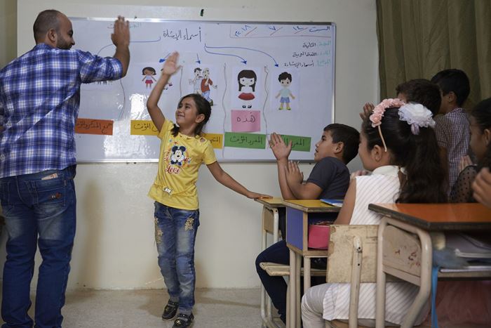 Reportage Libanon; Foto: Kind in der Schule gibt Erwachsenem "High Five" (Quelle: Ulrich Gernhardt / Kindernothilfe)