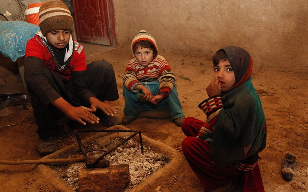 Reportage Pakistan: Das Leben riskieren, um zu überleben; Foto: Drei Kinder sitzen um Feuerstelle herum (Quelle: Christian Herrmanny / Kindernothilfe)
