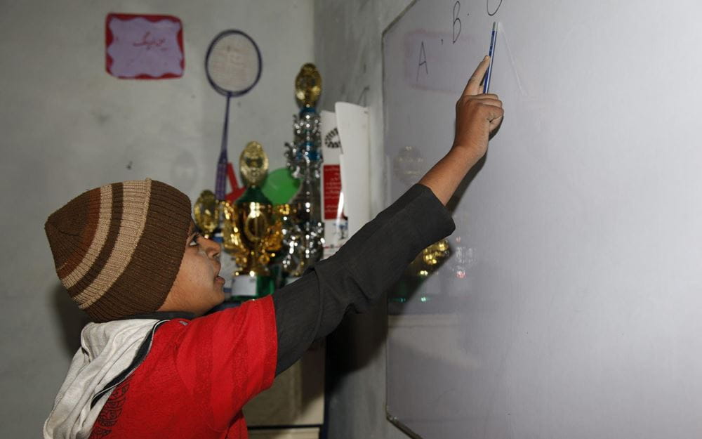 Reportage Pakistan: Das Leben riskieren, um zu überleben; Foto: Junge schreibt an Tafel  (Quelle: Christian Herrmanny / Kindernothilfe)