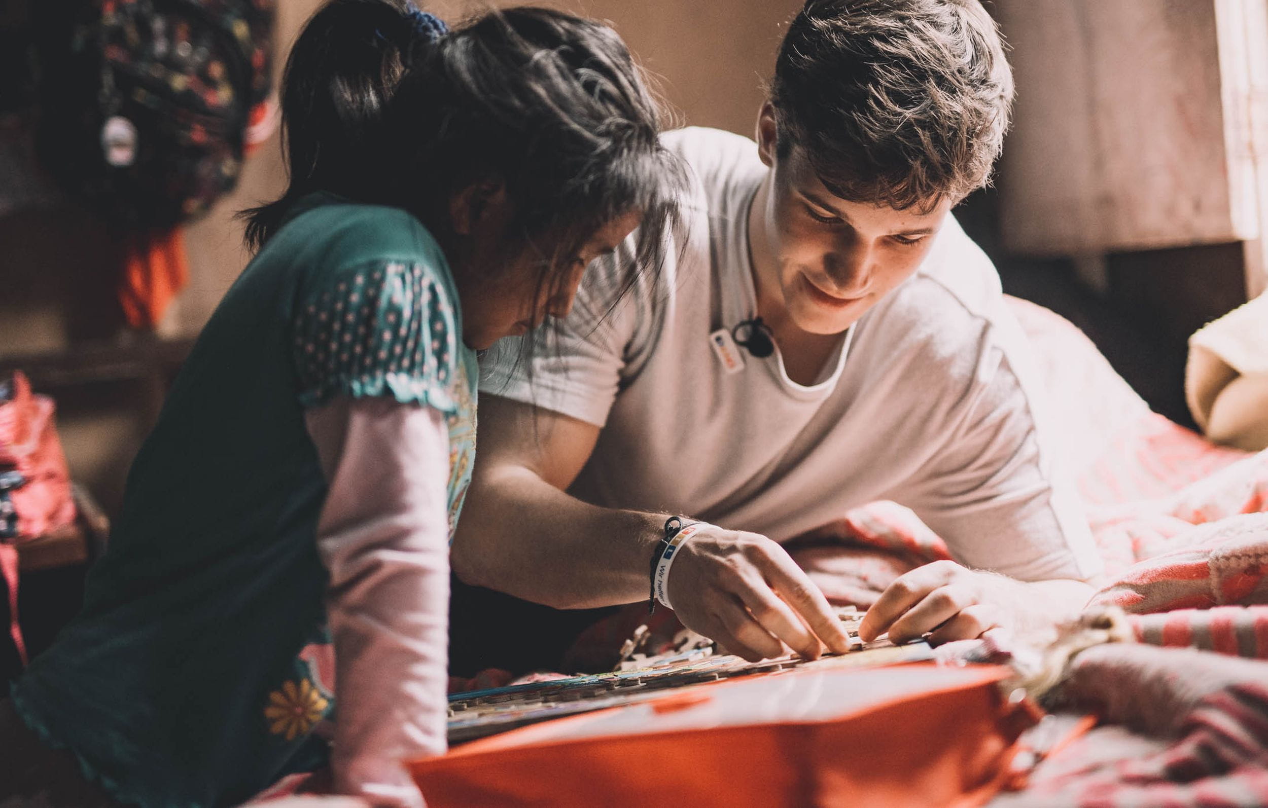 Reportage Peru: Kindernothilfe-Botschafter Wincent Weiss besucht ein Projekt; Foto: Wincent Weiss und Kind lösen ein Puzzle (Quelle: Christoph Köstlin / Kindernothilfe)