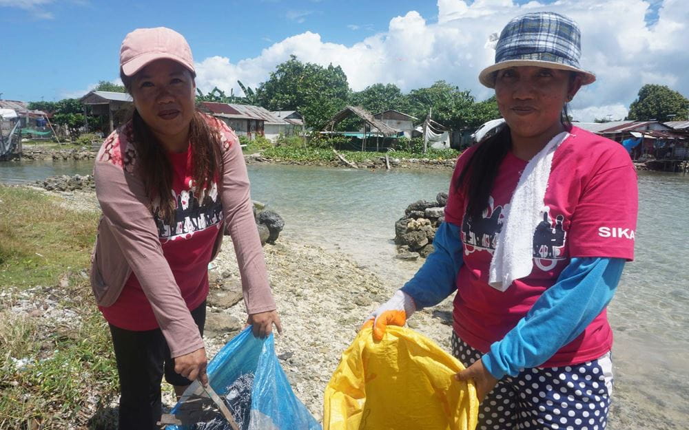 Reportage Philippinen: Ein Taifun als Weckruf; Foto: Zwei Frauen zeigen Inhalt ihrer Sammelsäcke in die Kamera  (Quelle: Ludwig Grunewald / Kindernothilfe)