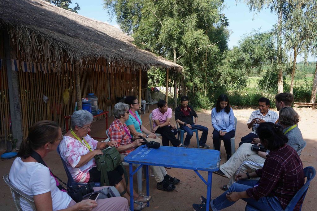 Reportage Thailand: Die Motoren des Wandels; Foto: Menschen sitzen auf Stühlen im Kreis vor einem Gebäude (Quelle: Kindernothilfe)