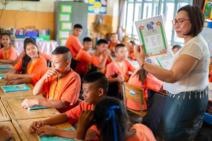 Kinder in Thailand folgen aufmerksam dem, was die Lehrerin erzählt. Die Kinder sind komplett in orange gekleidet. (Quelle: Jakob Studnar)