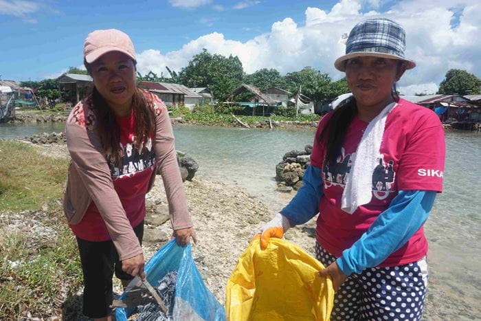 Zwei Frauen eine philippinische Selbsthilfegruppe halten einen Sack in den Händen. Darin sammeln sie Müll am Strand, um ihn zu säubern. (Quelle: Ludwig Grunewald)