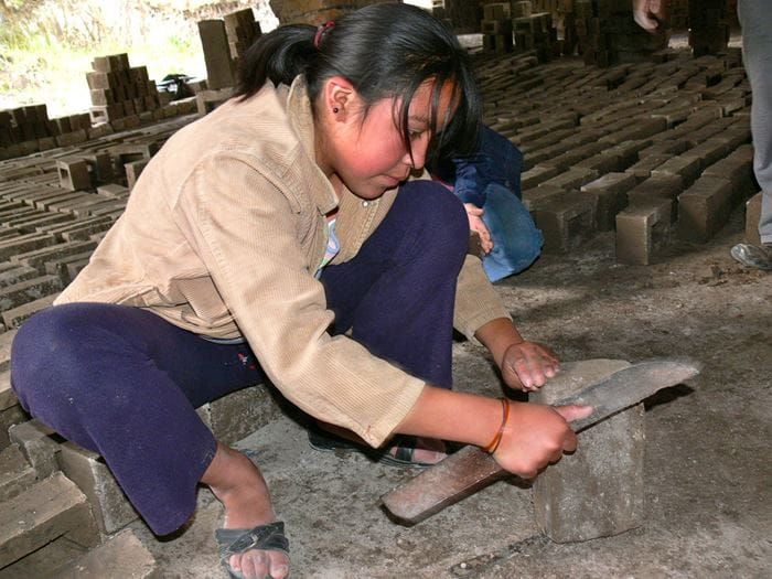 Ein Mädchen bearbeitet ein Stück Holz mit einem Messer. (Quelle: Jürgen Schübelin)