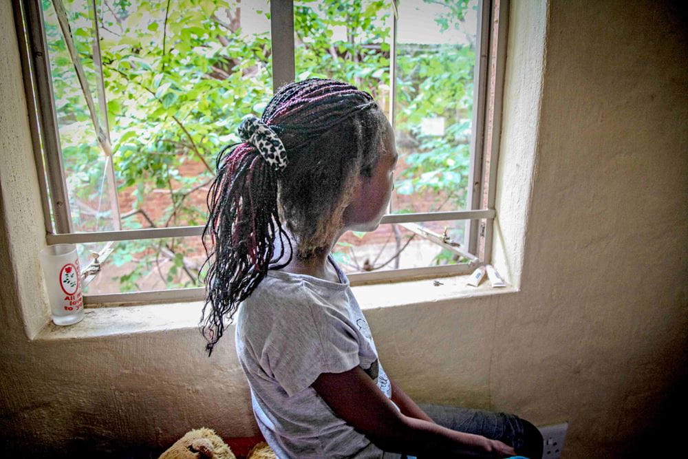 Ein Mädchen aus Südafrika blickt aus dem Fenster. Sie ist nur von hinten zu sehen, das Zimmer ist karg eingerichtet. (Quelle: Ralf Krämer) Ein Mädchen aus Südafrika blickt aus dem Fenster. Sie ist nur von hinten zu sehen, das Zimmer ist karg eingerichtet. (Quelle: Ralf Krämer)