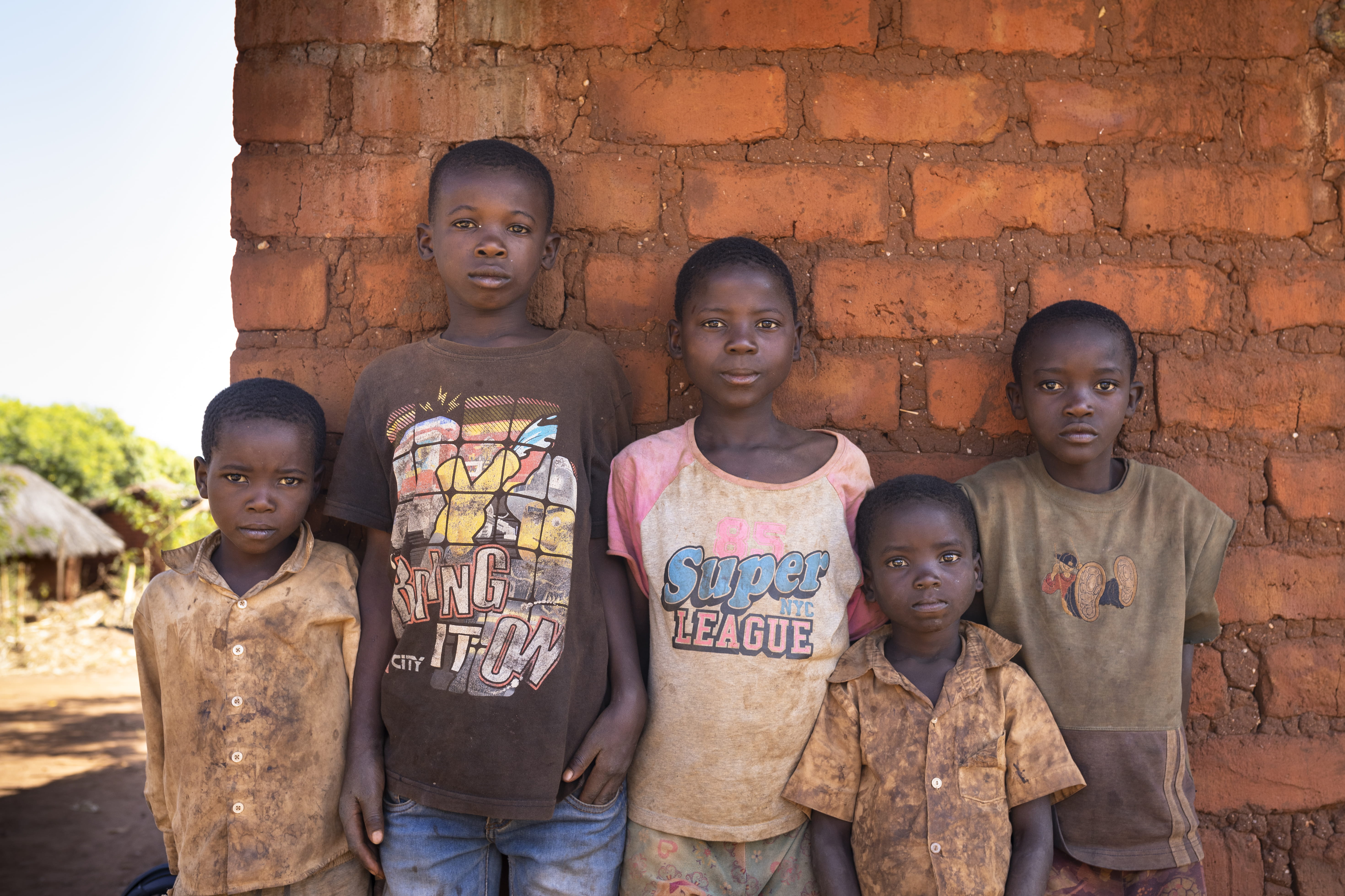 Fünf Jungen in verschmutzter Kleidung stehen traurig dreinblickend vor einer Hauswand. (Quelle: Christian O. Bruch)