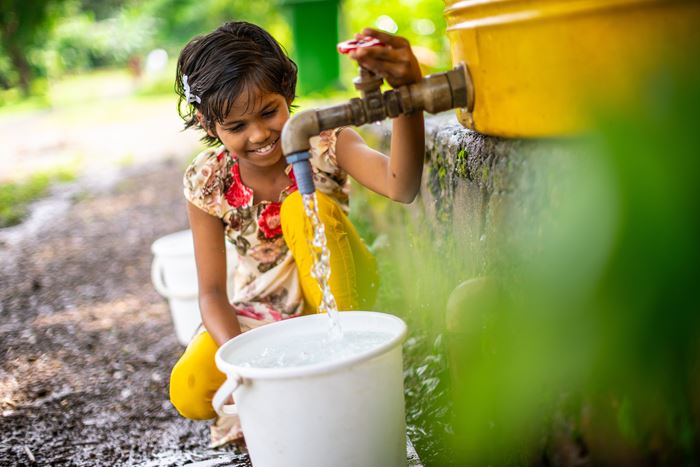 Ein Mädchen aus Indien füllt sauberes Wasser in einen gelben Kanister. (Quelle: Jako Studnar)