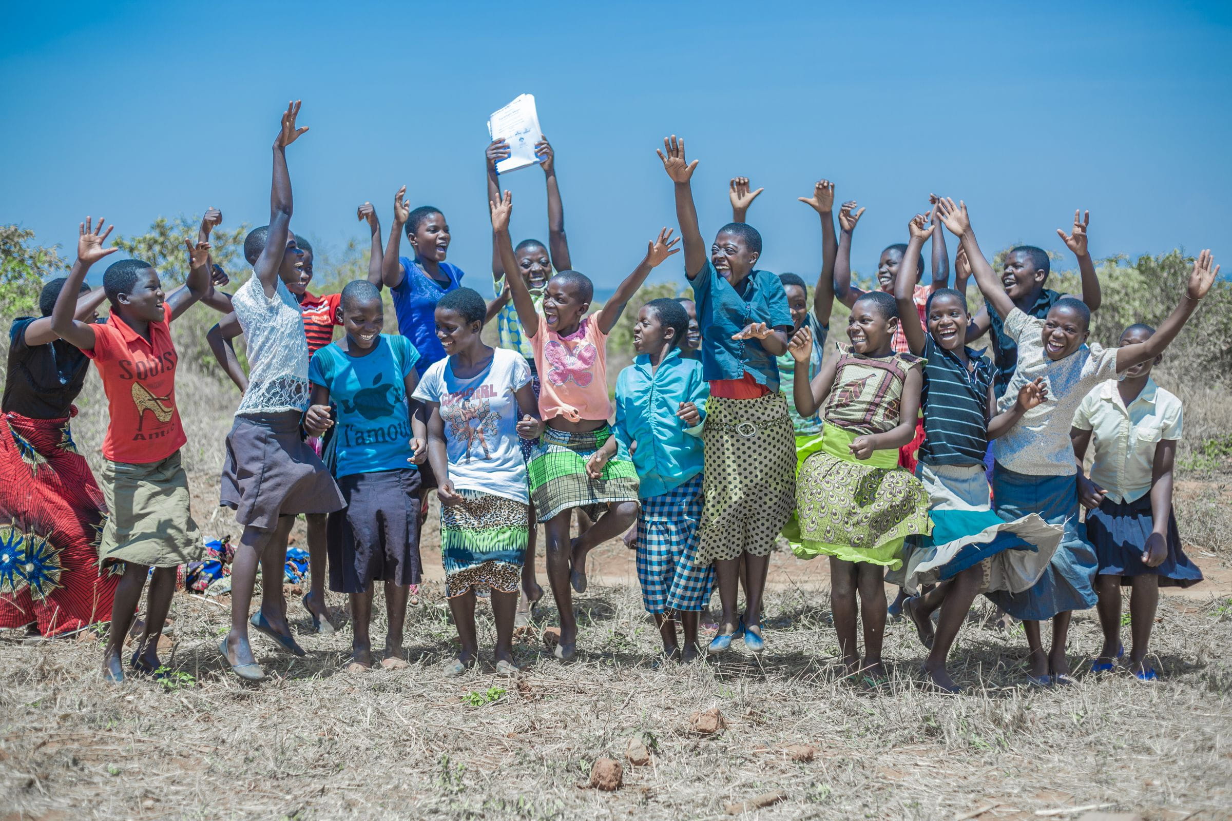 Kinder in Malawi springen glücklich lachend in die Luft. (Quelle: Moving Minds Multimedia)
