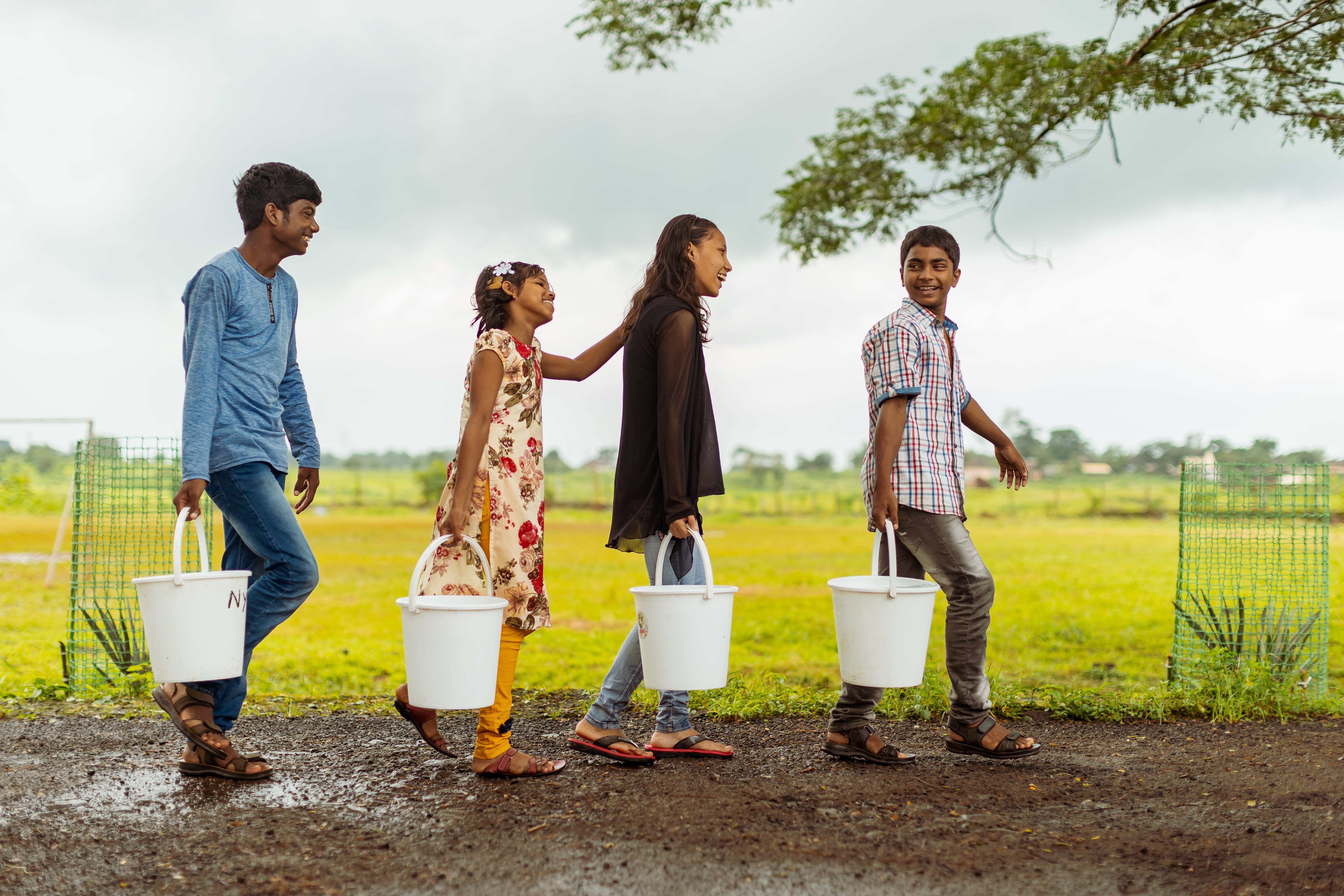 Wir Jugendliche aus Indien tragen Wassereimer und laufen hintereinander in einer Reihe. (Quelle: Jakob Studnar)