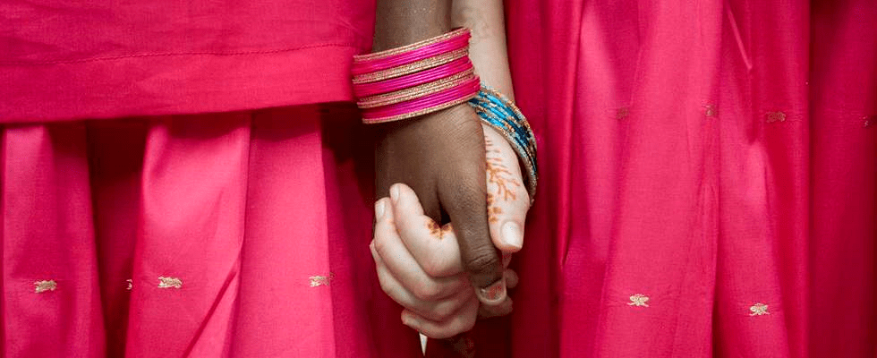 Zwei sich haltende Hände von zwei Mädchen in pinkem Gewand (Quelle: Kindernothilfe e.V.)