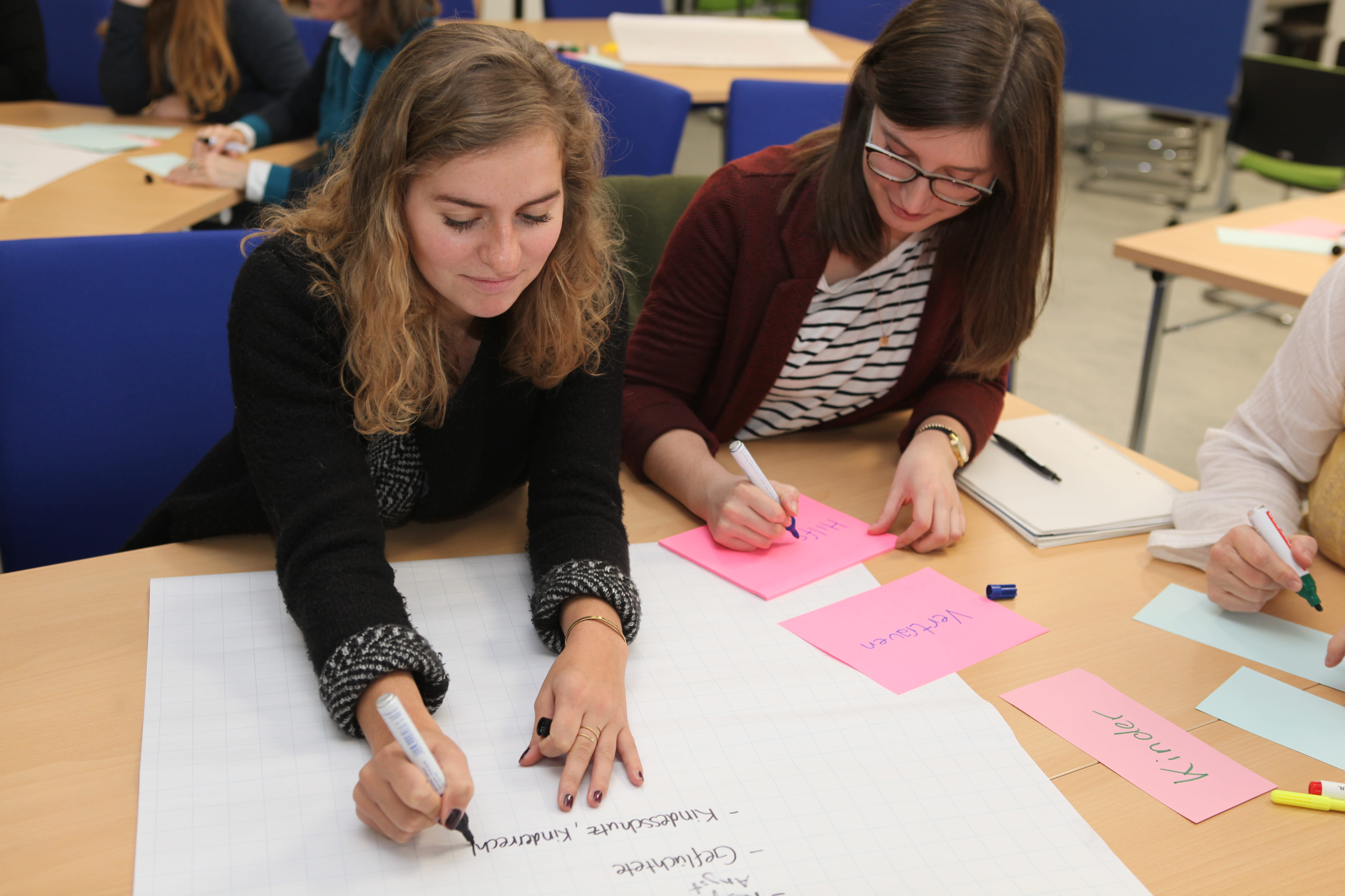 Zwei Schulungsteilnehmerinnen beschreiben Flipchart-Plakate und Metaplan-Karten (Quelle: Ludwig Grunewald, Kindernothilfe).